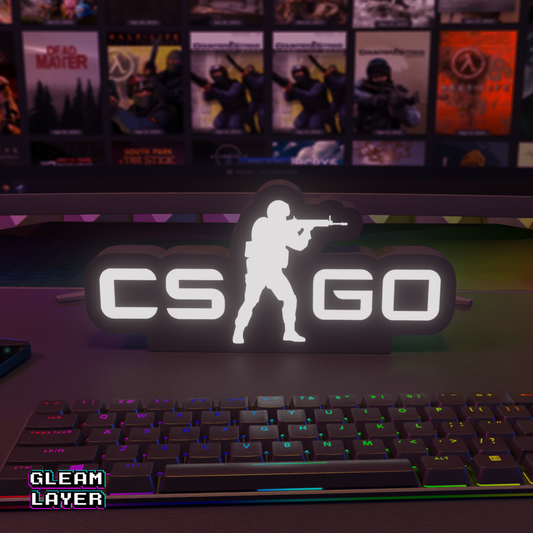 LED gaming light sign with 'CSGO' text and a silhouette of a character holding a gun placed on a desk in front of a computer setup.